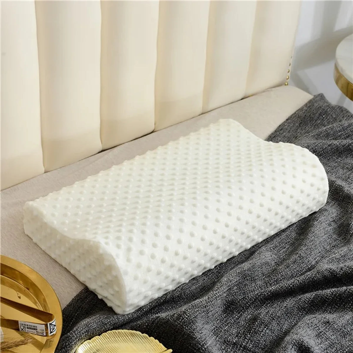 Le Nuage 50 posé sur un lit, plaid gris